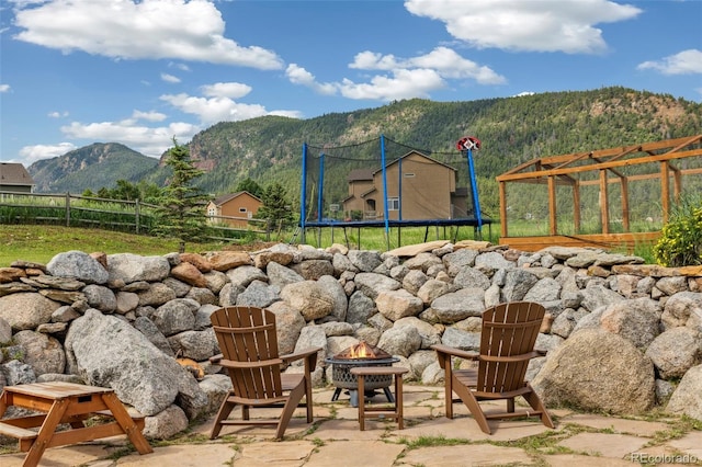 133 Wheat Ridge St, Palmer Lake, CO 80133 - view of patio featuring a fire pit, a trampoline, a mountain view, and a storage unit