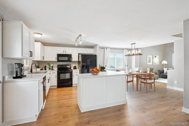 14625 Vine St, Thornton, CO 80602 - kitchen with black appliances, light countertops, a kitchen island, white cabinetry, and light wood-style floors