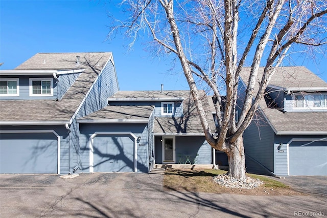 multi unit property featuring driveway, a shingled roof, and an attached garage