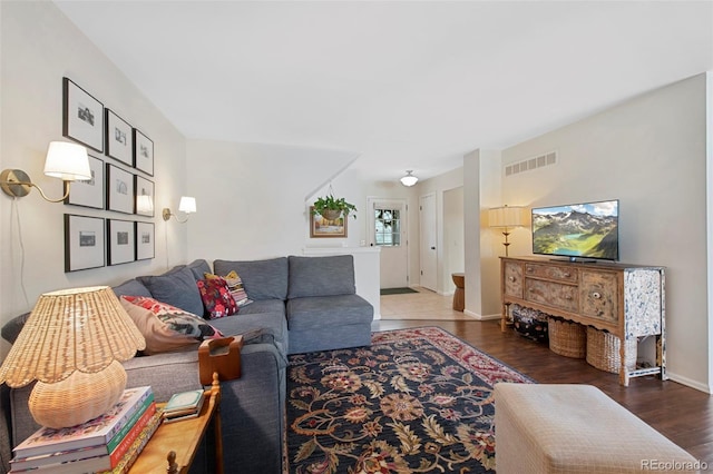 living room with wood finished floors, visible vents, and baseboards