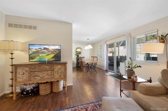 living area featuring visible vents, baseboards, and wood finished floors