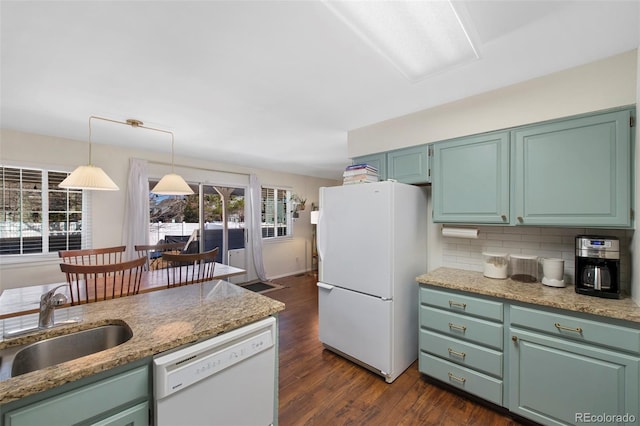 kitchen featuring white appliances, tasteful backsplash, dark wood finished floors, hanging light fixtures, and a sink