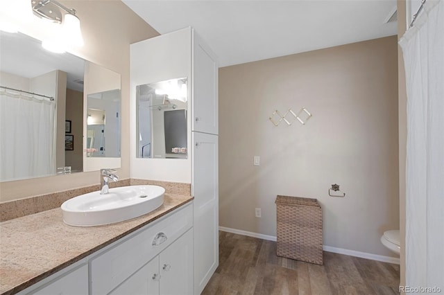 full bath with baseboards, vanity, toilet, and wood finished floors