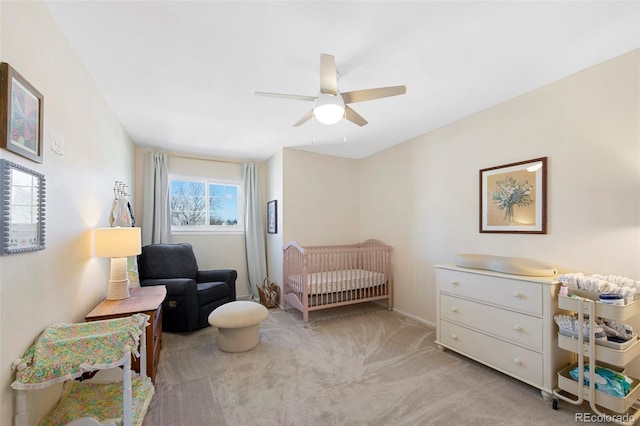 bedroom featuring a crib, a ceiling fan, and light colored carpet