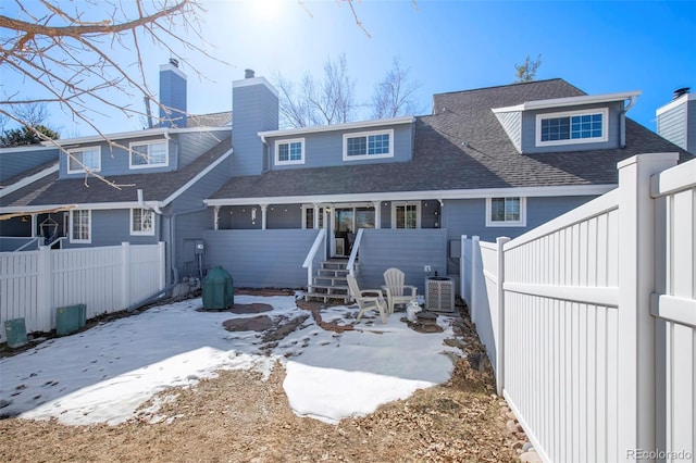 back of property with a shingled roof, fence, and a chimney