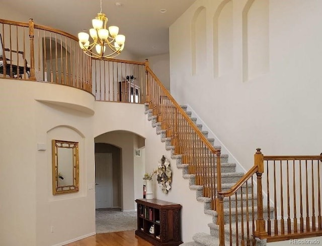 22386 E Arbor Pl, Aurora, CO 80016 - staircase with arched walkways, a chandelier, a towering ceiling, and wood finished floors