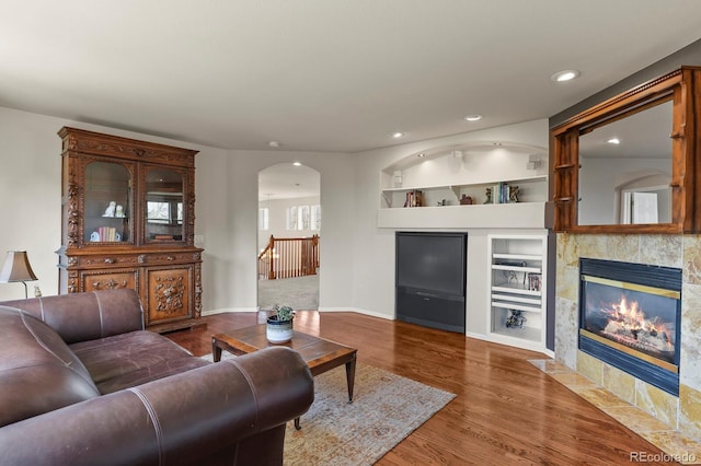 22386 E Arbor Pl, Aurora, CO 80016 - living room with arched walkways, built in features, recessed lighting, wood finished floors, and a tiled fireplace