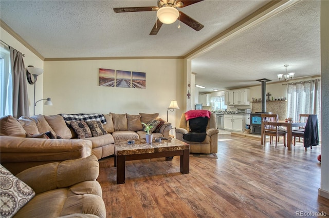 living room featuring ceiling fan with notable chandelier, crown molding, light hardwood / wood-style flooring, and a textured ceiling