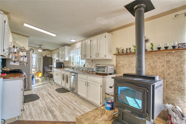 kitchen with ceiling fan, white cabinets, stainless steel dishwasher, crown molding, and light hardwood / wood-style floors