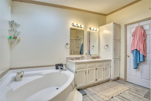 bathroom featuring a tub to relax in, hardwood / wood-style floors, vanity, crown molding, and a textured ceiling