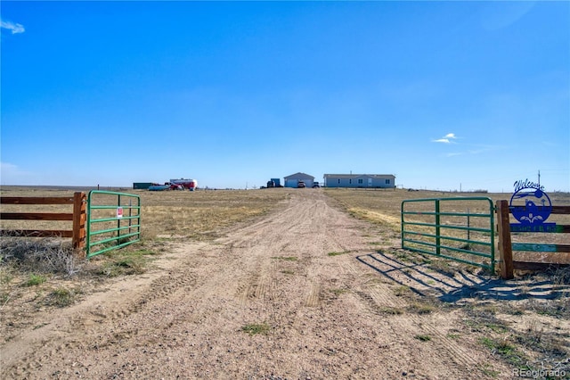 view of street featuring a gate, driveway, and a rural view