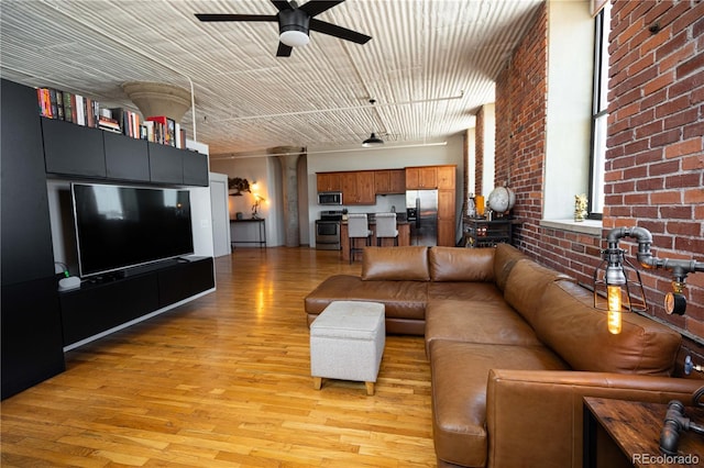 2261 Blake St Unit 5H, Denver, CO 80205 - living area featuring a ceiling fan, brick wall, and light wood-style floors