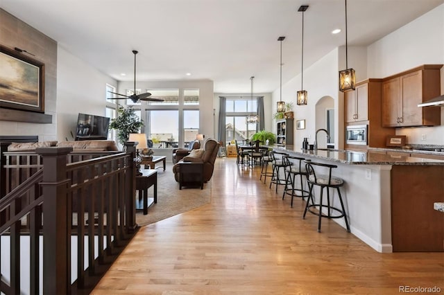18926 W 94th Ave, Arvada, CO 80007 - kitchen featuring stainless steel microwave, a breakfast bar, ceiling fan, light wood finished floors, and open floor plan