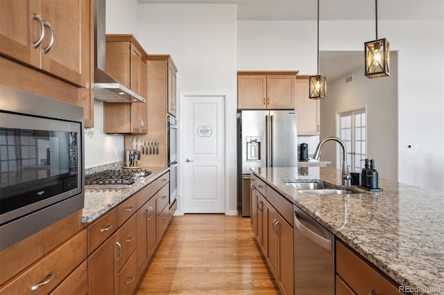 18926 W 94th Ave, Arvada, CO 80007 - kitchen featuring appliances with stainless steel finishes, wall chimney range hood, light wood-style flooring, and light stone countertops