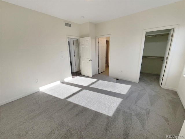 unfurnished bedroom featuring a closet, a spacious closet, and light carpet