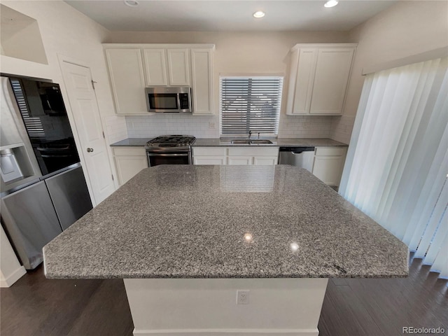 kitchen with sink, white cabinets, a center island, stainless steel appliances, and light stone countertops