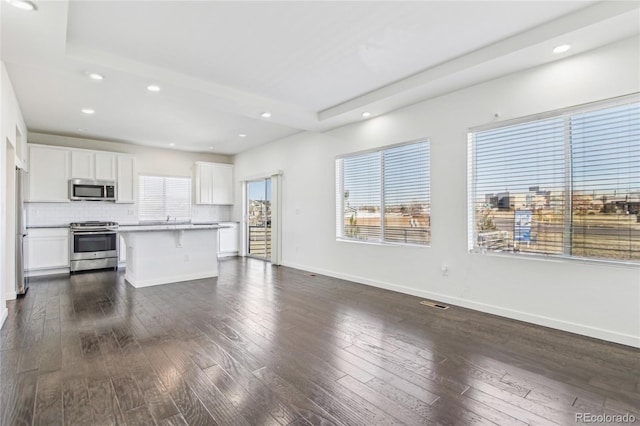 kitchen featuring dark wood-type flooring, stainless steel appliances, a center island, and white cabinets