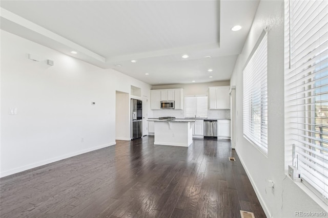 unfurnished living room featuring dark hardwood / wood-style flooring and a tray ceiling