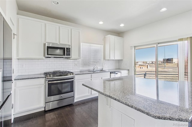 kitchen featuring sink, stainless steel appliances, dark hardwood / wood-style floors, light stone counters, and white cabinets