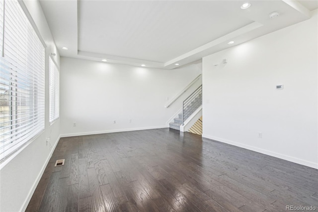 unfurnished living room featuring a tray ceiling and dark wood-type flooring