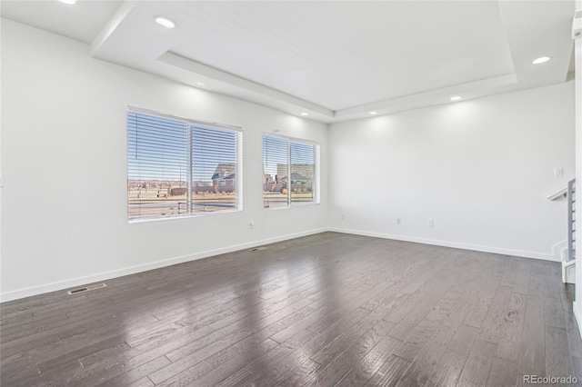 unfurnished room with a raised ceiling and dark hardwood / wood-style flooring