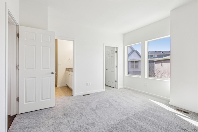 unfurnished bedroom with ensuite bath and light carpet