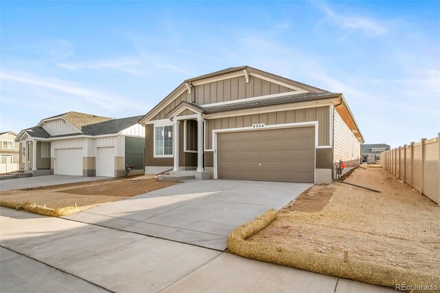 22384 E 49th Pl, Aurora, CO 80019 - view of front of property featuring concrete driveway, a shingled roof, board and batten siding, and an attached garage
