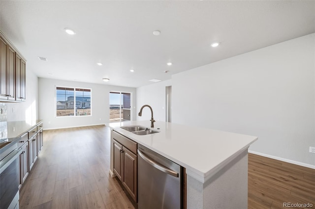 22384 E 49th Pl, Aurora, CO 80019 - kitchen with stainless steel dishwasher, wood finished floors, light countertops, a kitchen island with sink, and recessed lighting