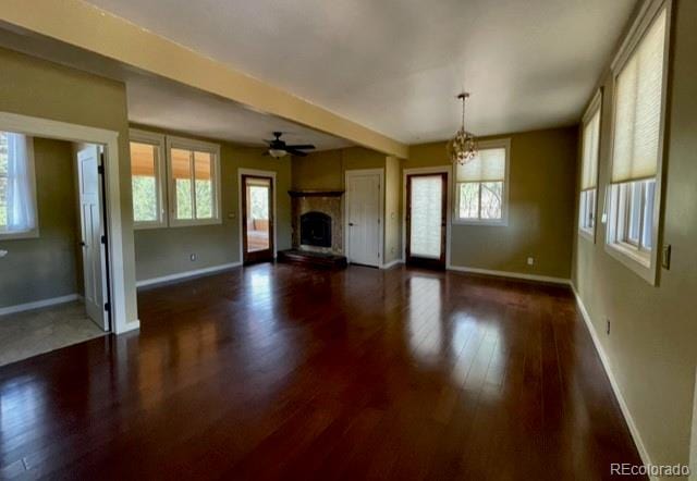 unfurnished living room featuring dark wood-type flooring and ceiling fan with notable chandelier