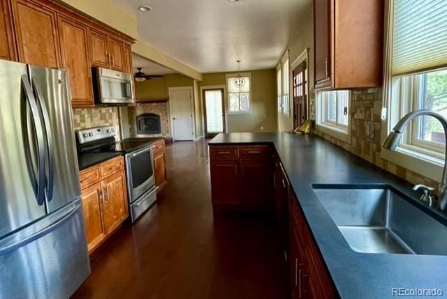 kitchen with tasteful backsplash, stainless steel appliances, decorative light fixtures, dark wood-type flooring, and sink