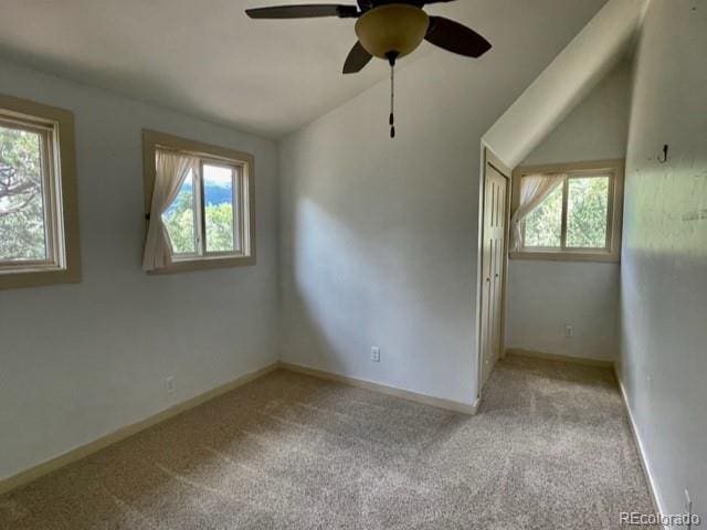 empty room featuring a wealth of natural light, carpet flooring, ceiling fan, and lofted ceiling