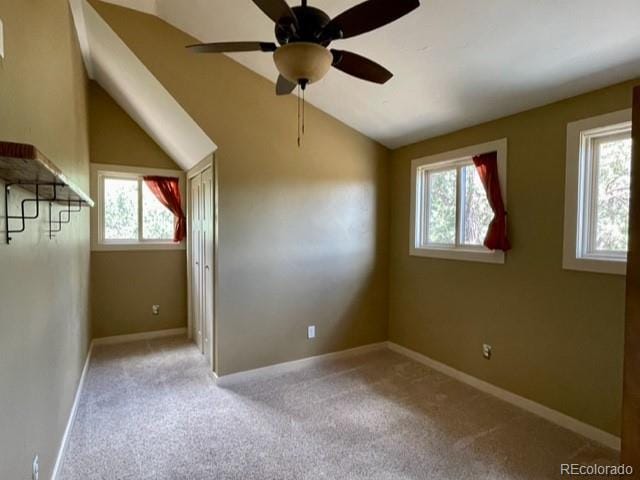 carpeted empty room with ceiling fan, vaulted ceiling, and a wealth of natural light