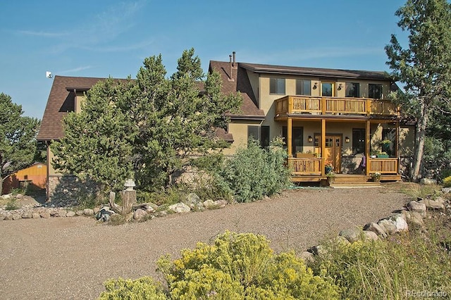 view of front facade with covered porch, a balcony, and stucco siding