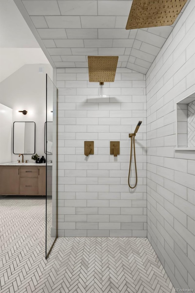 bathroom featuring vanity, lofted ceiling, and tiled shower