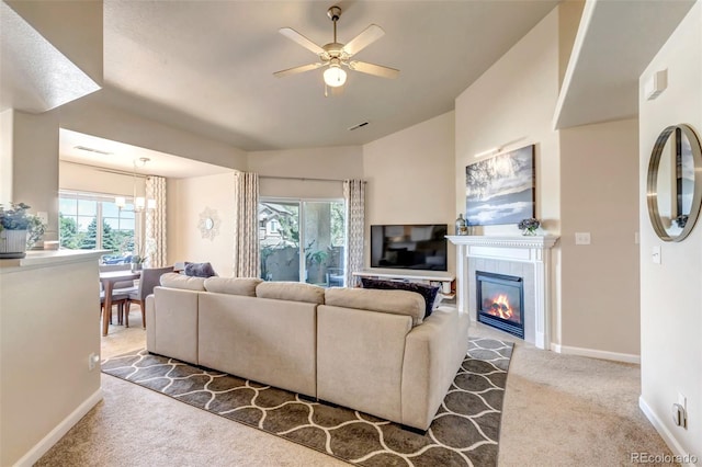 living room featuring vaulted ceiling, a fireplace, carpet flooring, and ceiling fan with notable chandelier