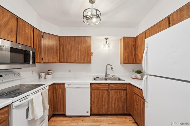 2393 E 90th Ave, Thornton, CO 80229 - kitchen with white appliances, a sink, brown cabinetry, light countertops, and light wood-style floors