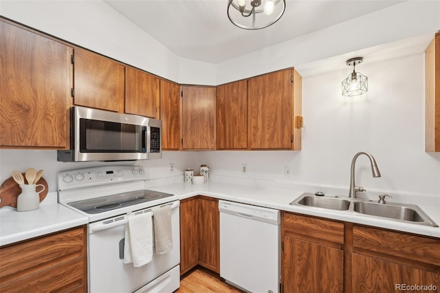 2393 E 90th Ave, Thornton, CO 80229 - kitchen with white appliances, a sink, brown cabinetry, light countertops, and light wood-style flooring
