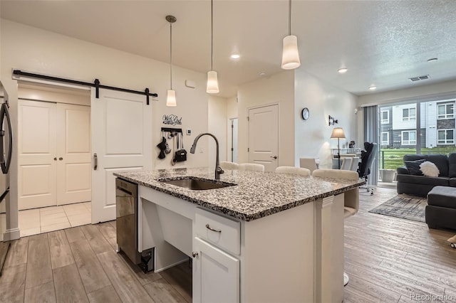 16841 Askins Loop Unit 105, Parker, CO 80134 - kitchen featuring a sink, a barn door, open floor plan, light wood-style flooring, and white cabinets