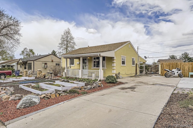 bungalow with fence, stucco siding, a vegetable garden, concrete driveway, and covered porch