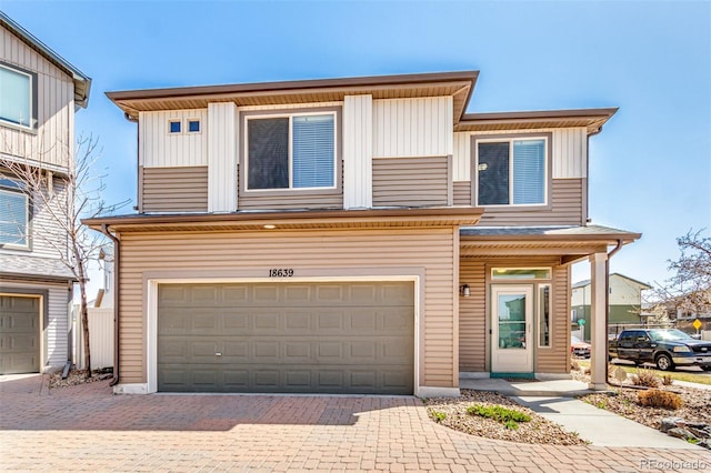 view of front of home featuring board and batten siding, decorative driveway, and a garage