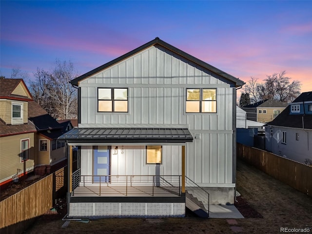 back house at dusk featuring a porch