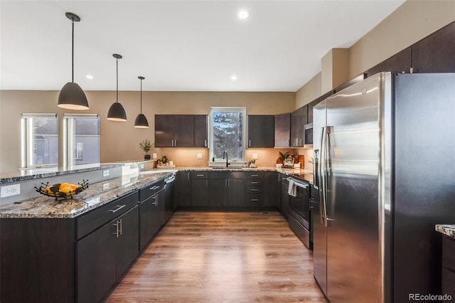 kitchen featuring kitchen peninsula, pendant lighting, dark brown cabinetry, and stainless steel appliances