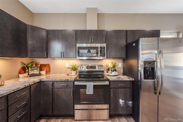 kitchen featuring dark brown cabinets, stainless steel appliances, and light stone counters