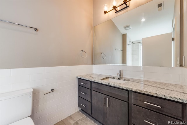 bathroom featuring tile walls, toilet, and vanity