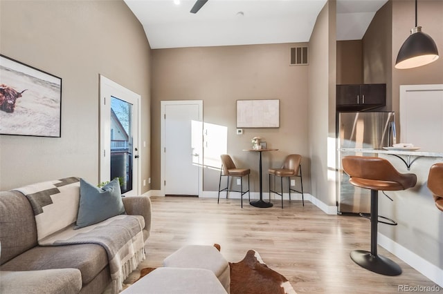 living room featuring light wood-type flooring, vaulted ceiling, and ceiling fan