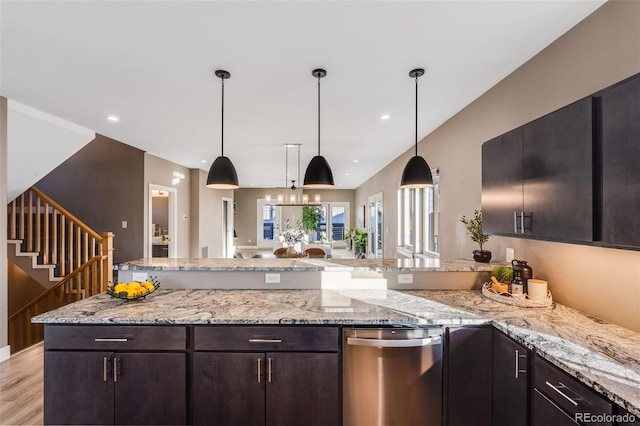 kitchen with dark brown cabinets, hanging light fixtures, light hardwood / wood-style floors, and light stone counters