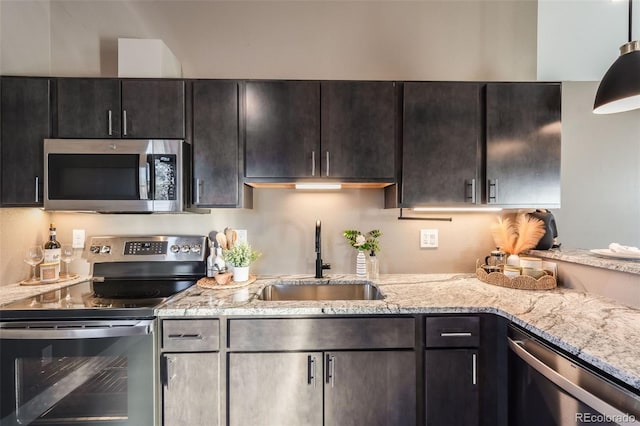 kitchen with stainless steel appliances, sink, hanging light fixtures, light stone counters, and dark brown cabinets