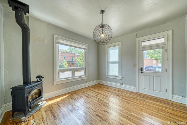 144 N C St, Salida, CO 81201 - unfurnished living room with a wood stove, wood finished floors, a textured wall, and baseboards