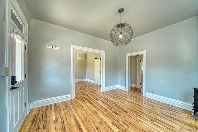 144 N C St, Salida, CO 81201 - empty room with light wood-style floors, baseboards, a chandelier, and a wood stove