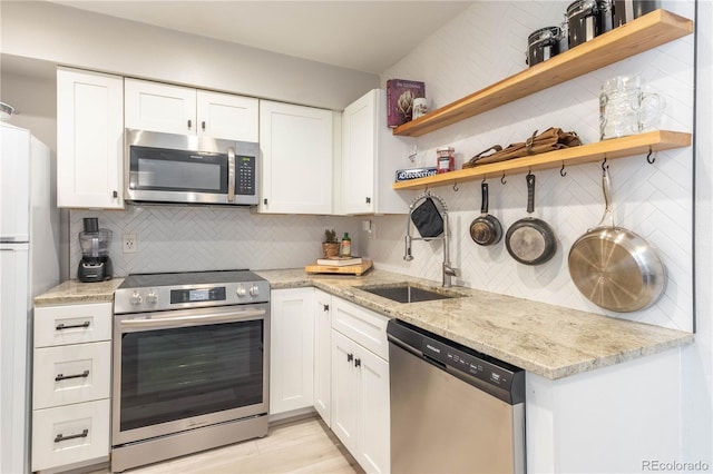 kitchen featuring light stone countertops, appliances with stainless steel finishes, decorative backsplash, and white cabinetry